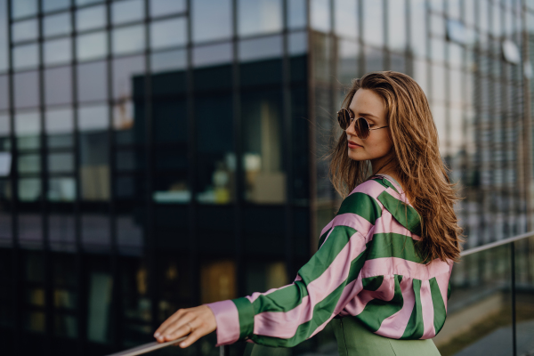 Portrait of beautiful young woman outdoor in a city, during sunset.