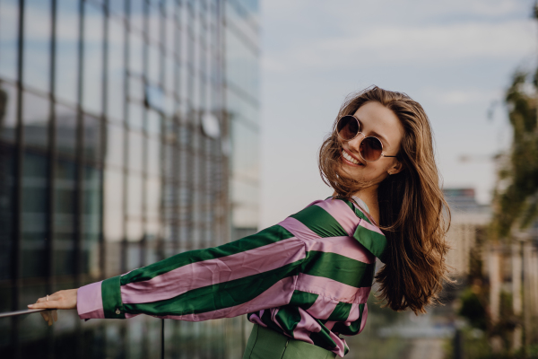 Portrait of beautiful young woman outdoor in a city, during sunset.