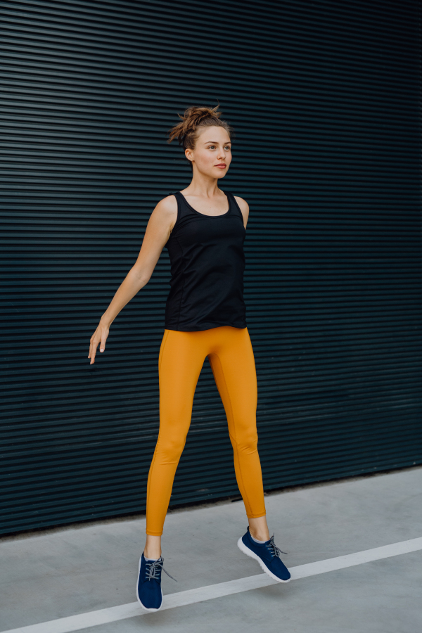 Portrait of young excited woman jumping outdoor in a city.