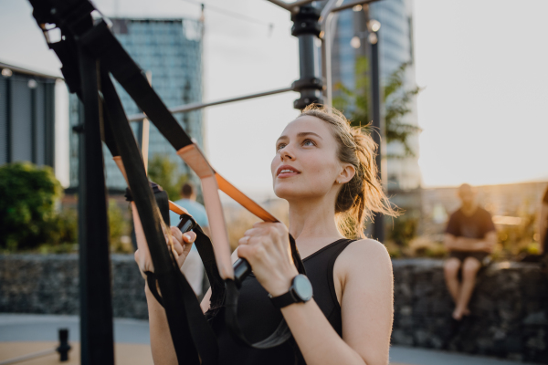 Happy young woman doing exercises at outdoor work-out city park.