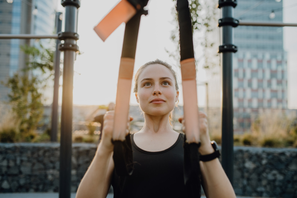 Happy young woman doing exercises at outdoor work-out city park.