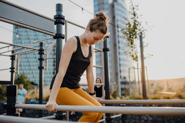 Happy young woman doing exercises at outdoor work-out city park.