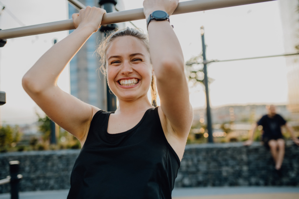 Happy young woman doing exercises at outdoor work-out city park.