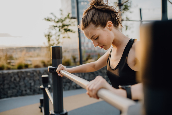 Happy young woman doing exercises at outdoor work-out city park.