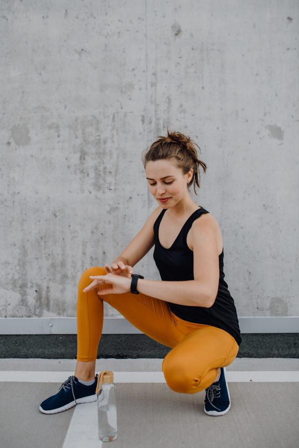 Young woman doing stretching in a city, preparing for run, healthy lifestyle and sport concept.