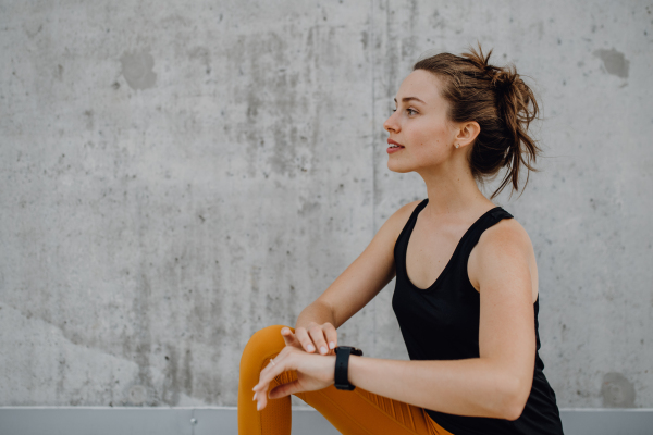 Young woman doing stretching in a city, preparing for run, healthy lifestyle and sport concept.