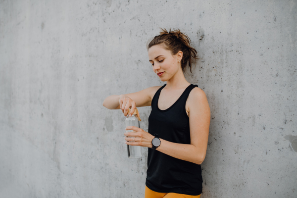 Young woman drinking water during jogging in a city, healthy lifestyle and sport concept.