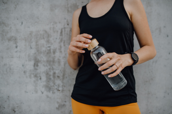 Young woman drinking water during jogging in a city, healthy lifestyle and sport concept.