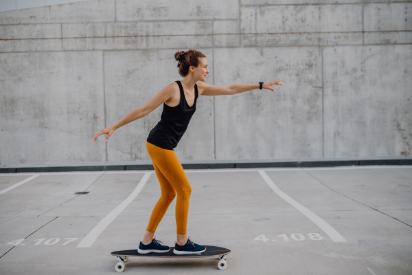 Young woman ridding a skateboard at city. Youth culture and commuting concept.