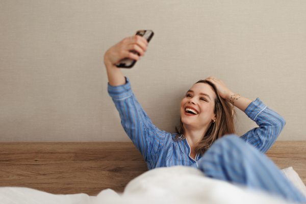 Young happy woman taking selfie in a bed.