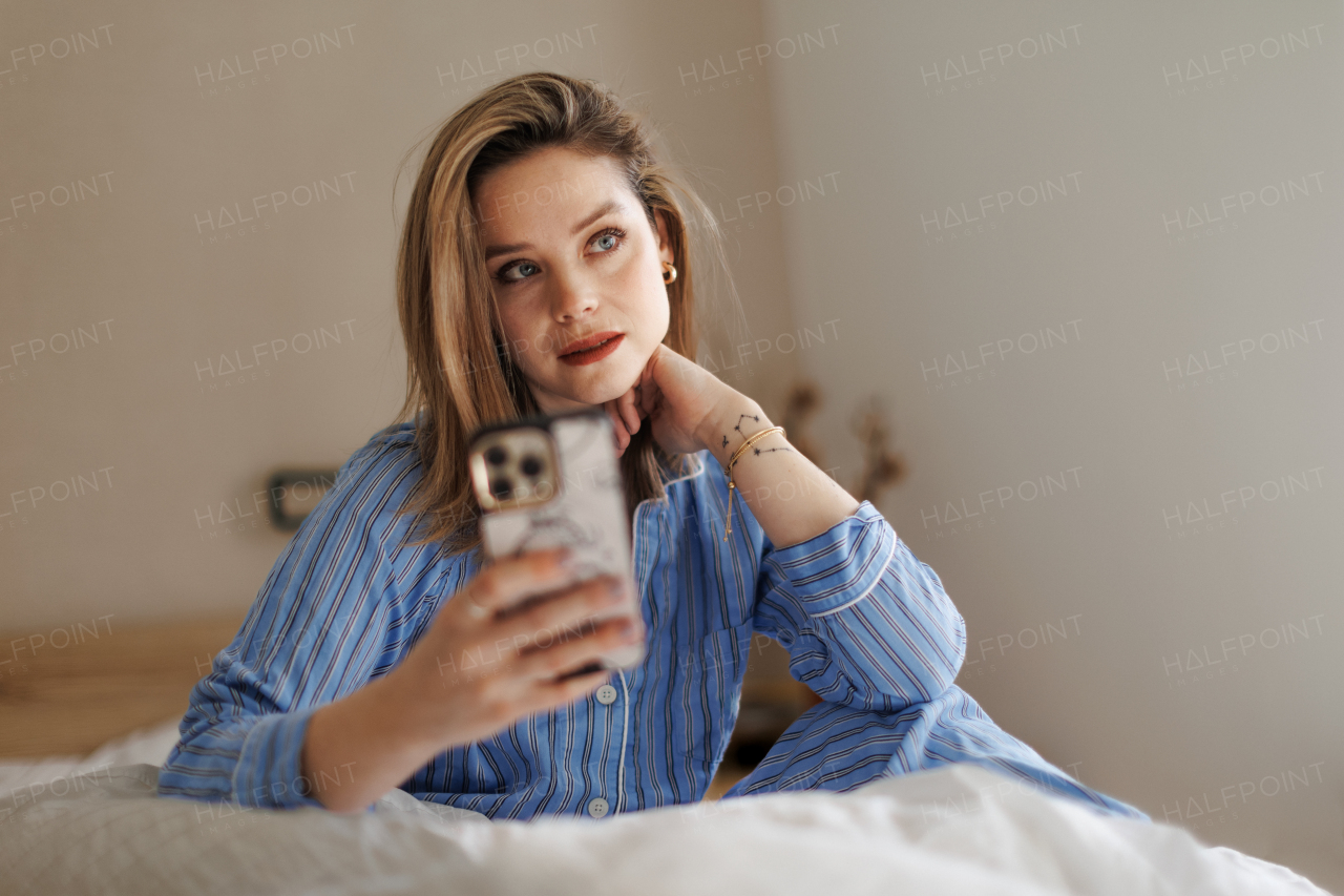 Young happy woman taking photo in a bed.