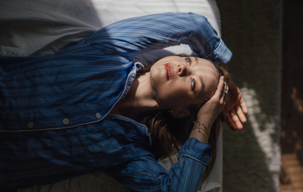 Top view of woman lying in a bed,morning sun shining on her face.