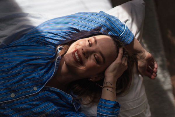 Top view of woman lying in a bed,morning sun shining on her face.