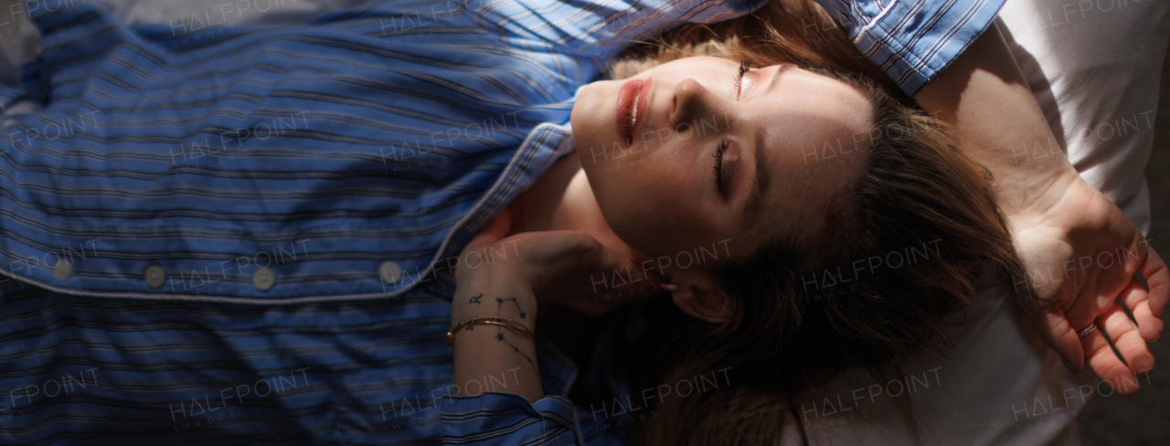 Top view of woman lying in a bed,morning sun shining on her face.