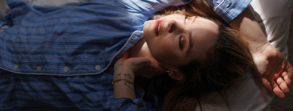 Top view of woman lying in a bed,morning sun shining on her face.