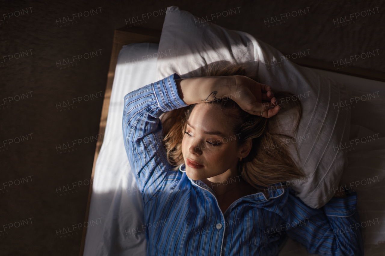 Top view of woman lying in a bed,morning sun shining on her face.