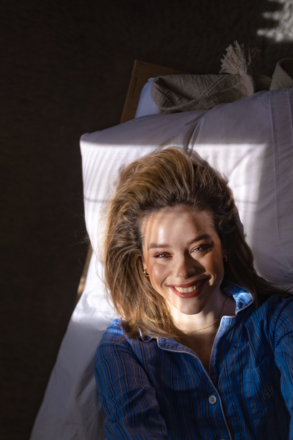 Top view of woman lying in a bed,morning sun shining on her face.