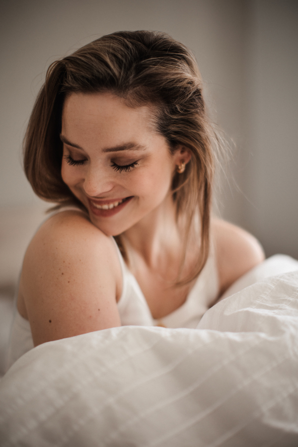 Portrait of young woman at morning in a bed.