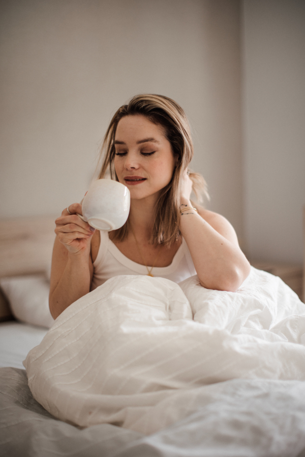 Portrait of young woman at morning in a bed.