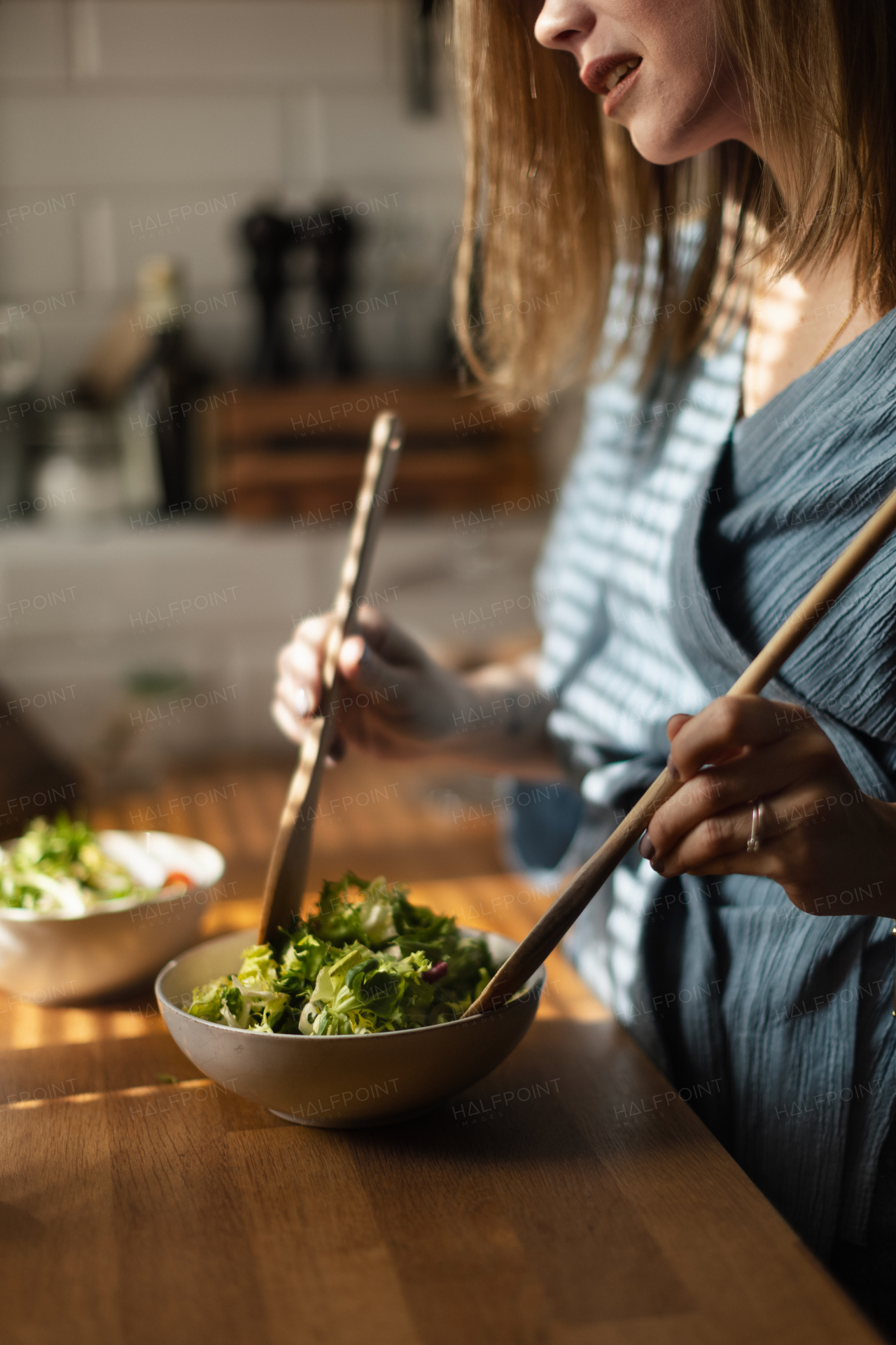 Young woman preparing salad in the kitchen.