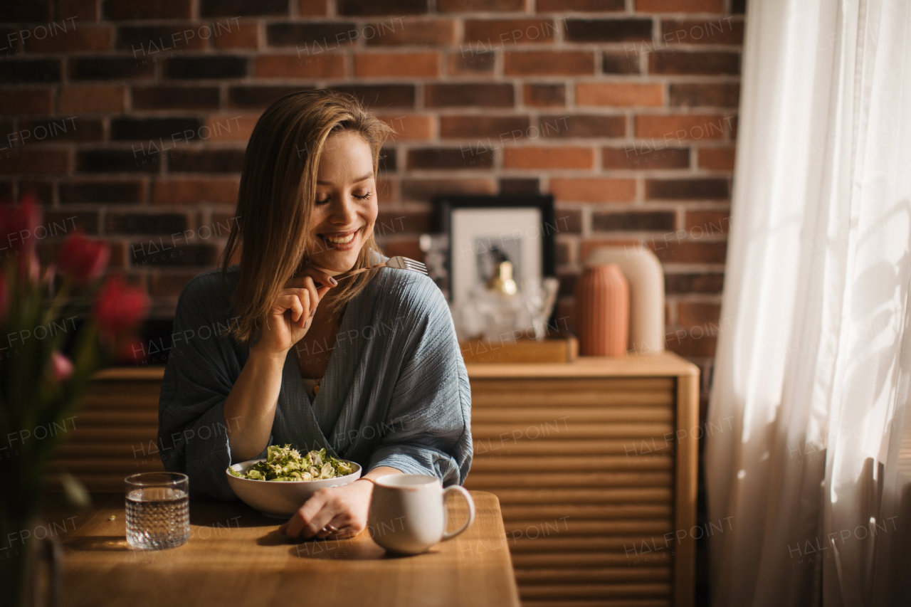 Young woman eating salad in the kitchen, concept of healthy eating.