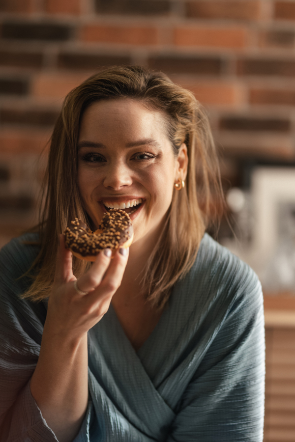 Young happy woman eating donuts in the cafe.