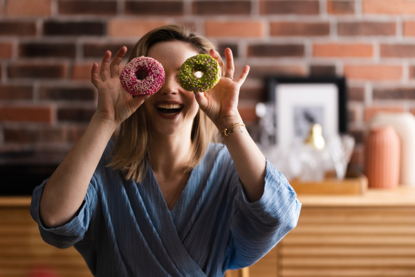 Young happy woman posing with donuts in the cafe.