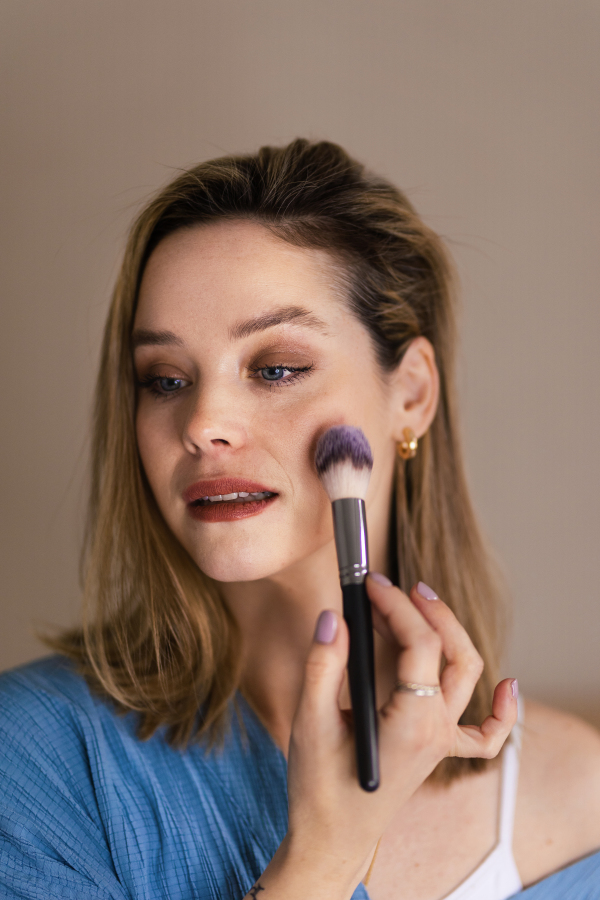 Young woman doing her make-up with a brush.