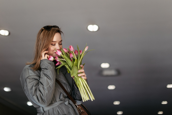 Young woman calling in a city with bouquet of tulips.