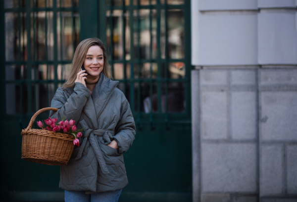 Young woman calling in a city with bouquet of tulips.