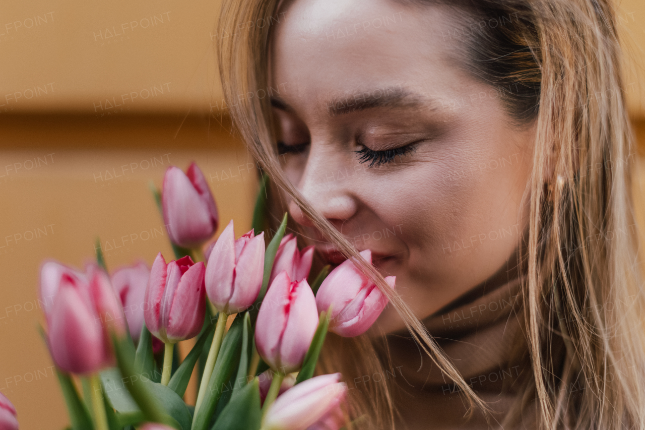 Young woman calling in a city with bouquet of tulips.