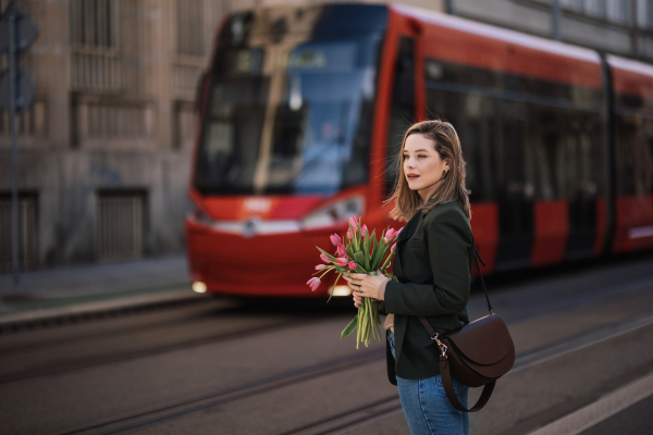 Portrait of young woman in a city with bouquet of tulips.