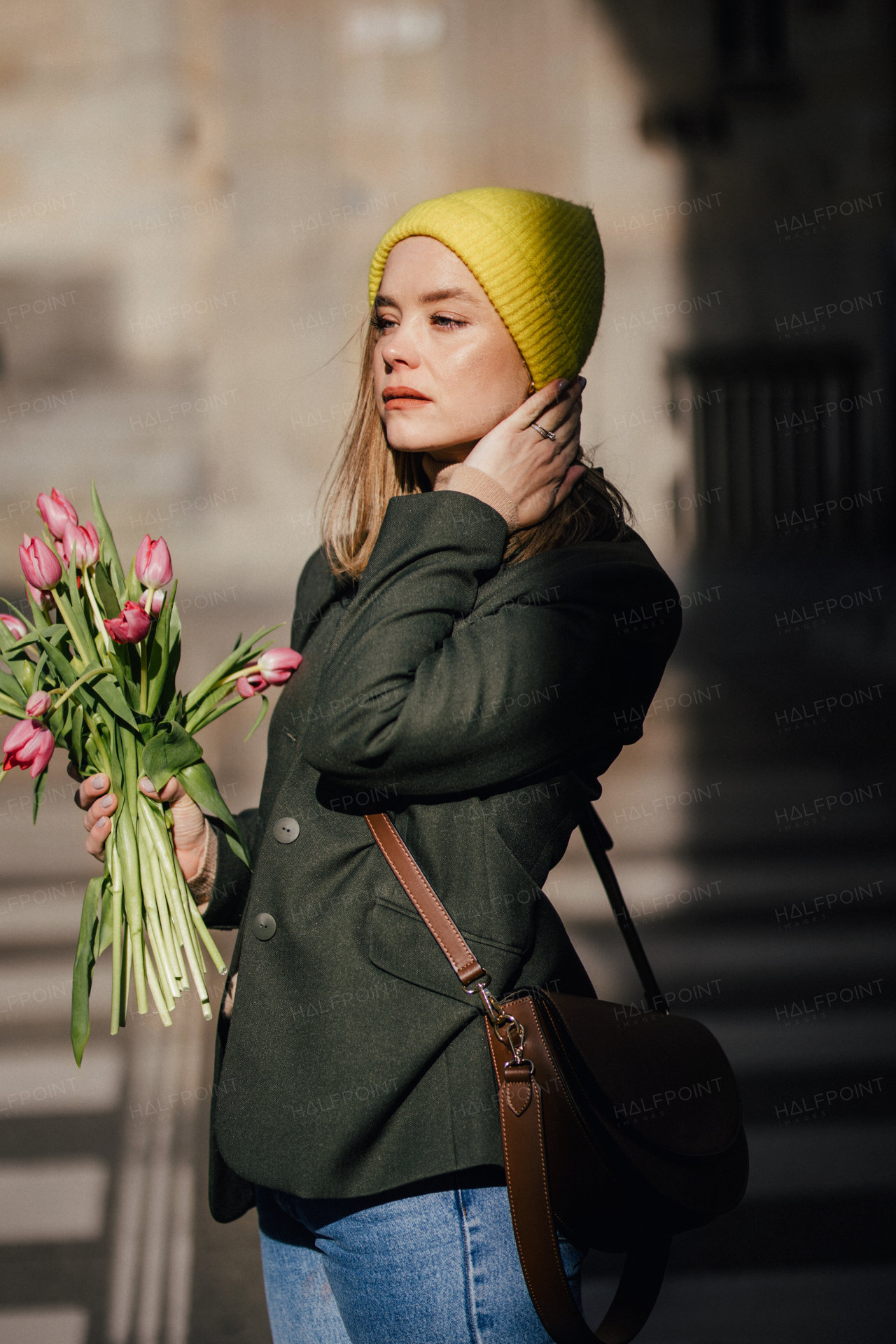 Portrait of young woman in a city with bouquet of tulips.