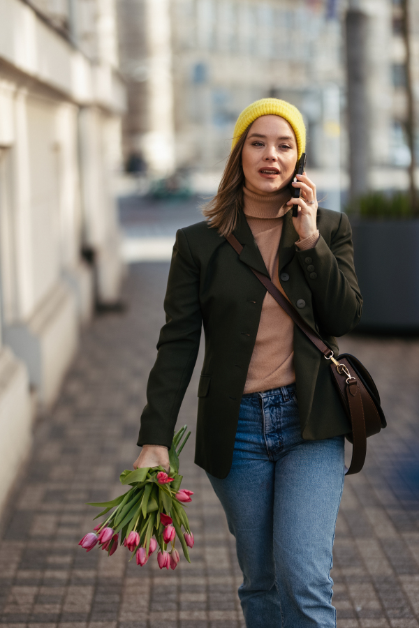 Young woman walking in a city with tulips and calling.