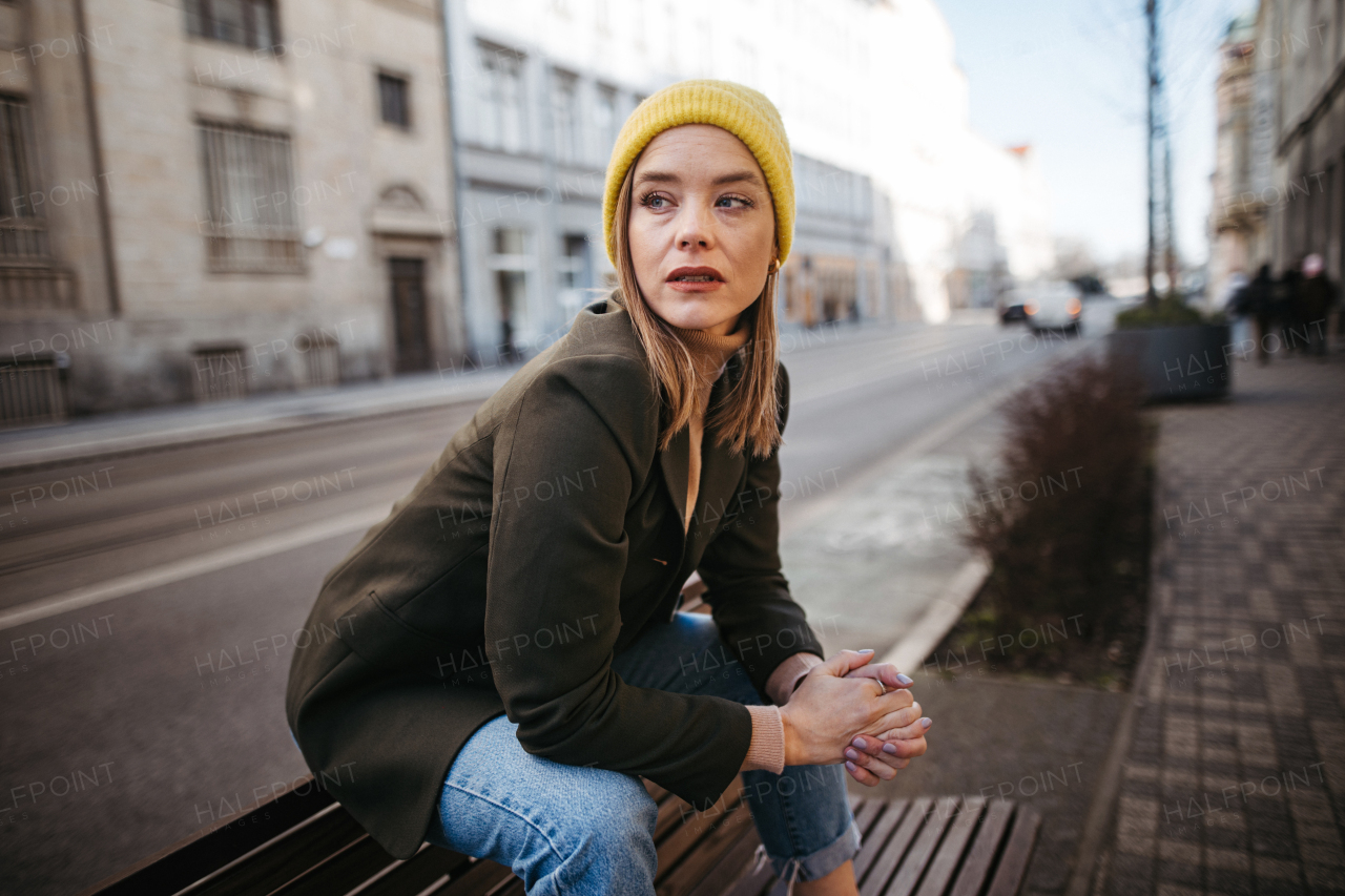 Young fashionable woman sitting on bench in a city.