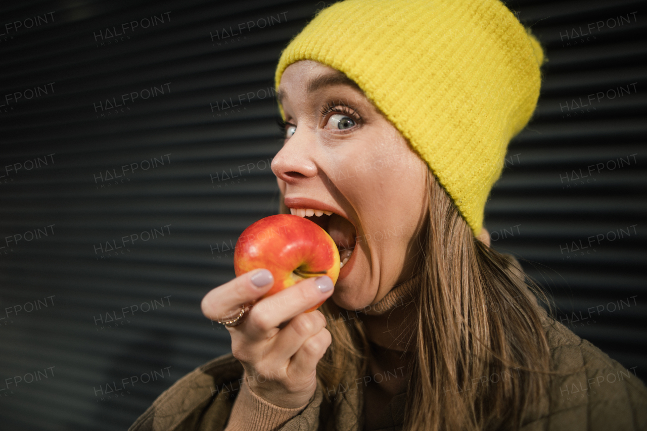 Portrait of young fashionable woman eating an apple.