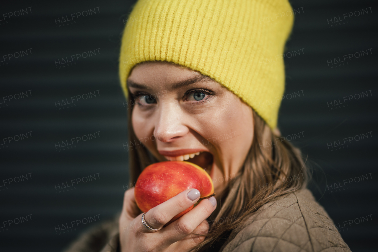 Portrait of young fashionable woman eating an apple.