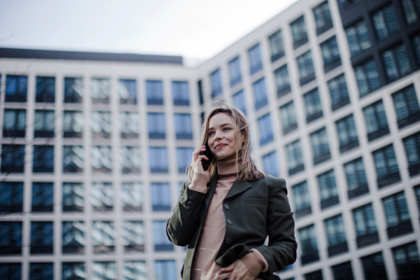 Portrait of young fashionable woman in city calling.