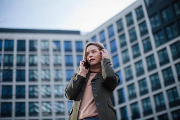 Portrait of young fashionable woman in city calling.