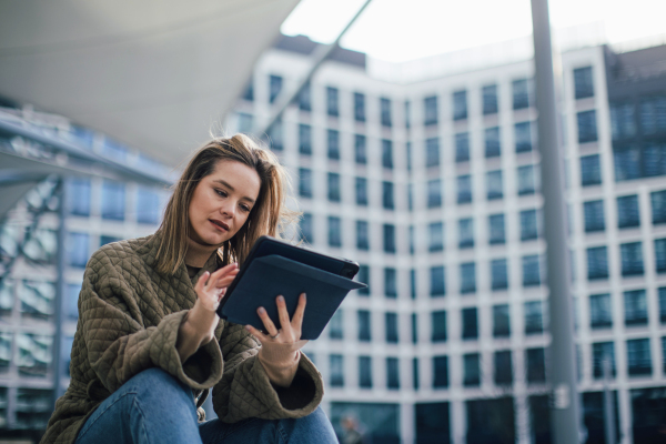 Portrait of young fashionable woman in city with digital tablet.