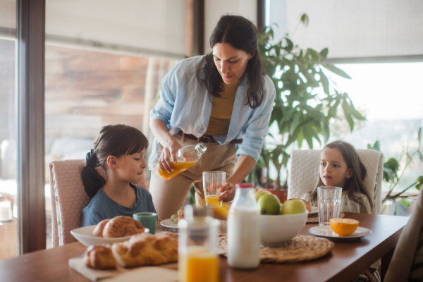 Mother prepares breakfast for the children, in the morning. Maternal love and care for the household and family.