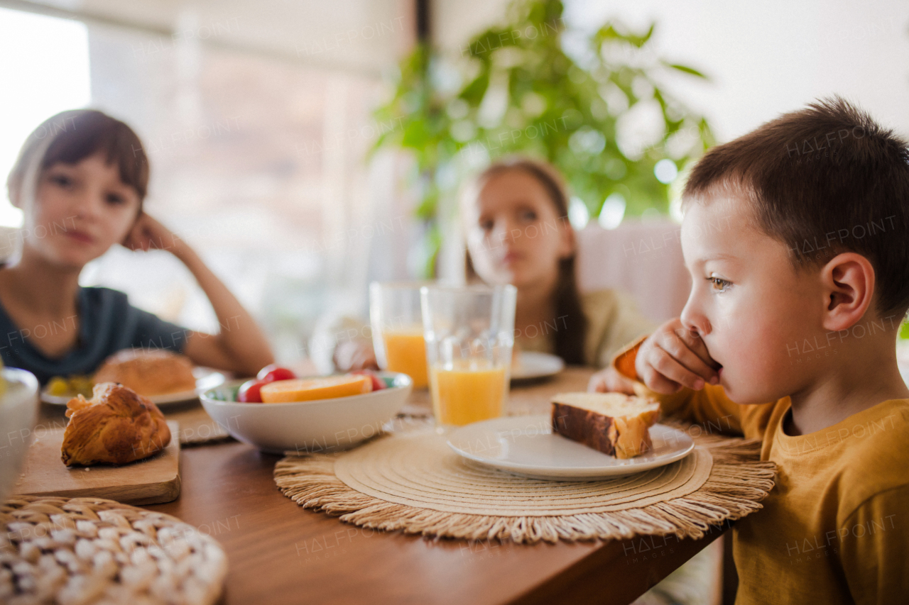 Three siblings eating breakfast in the morning, before school. Back to school, eating homemade breakfast. Importance of eating breakfast before school.