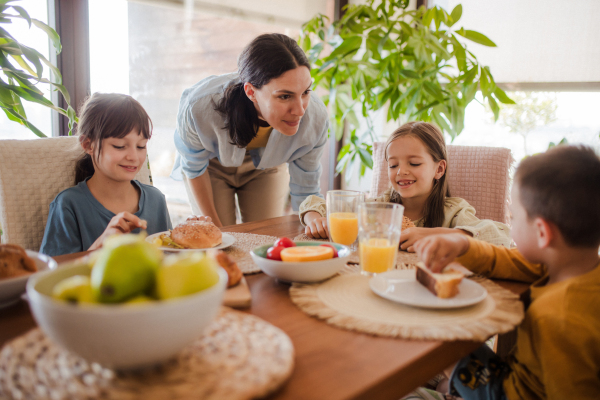 Mother prepares breakfast for the children, in the morning. Maternal love and care for the household and family.