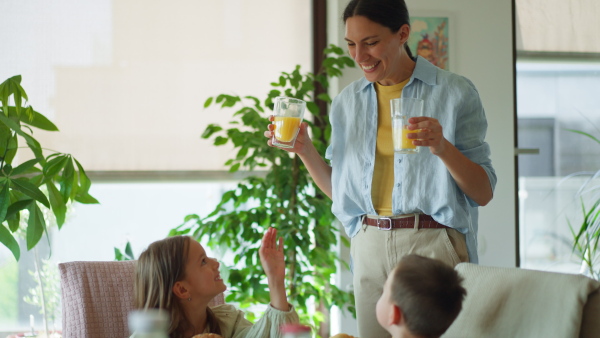 Mother prepares breakfast and pouring juice for the children, in the morning. Maternal love and care for the household and family.