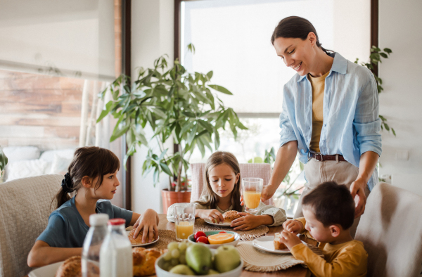 Mother prepares breakfast for the children, in the morning. Maternal love and care for the household and family.