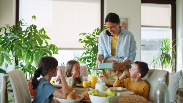 Mother prepares breakfast and pouring juice for the children, in the morning. Maternal love and care for the household and family.