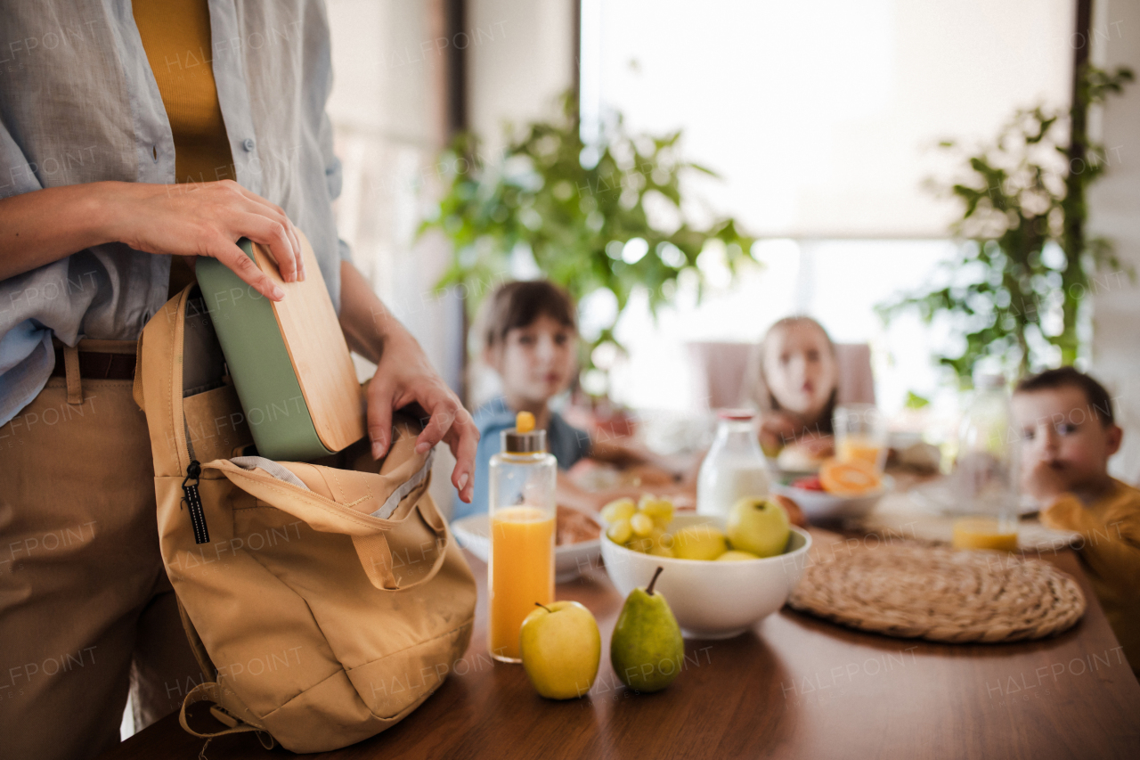 Mother packing school snacks for her children into school bag. Snack, school lunch in a snack box, container for school.