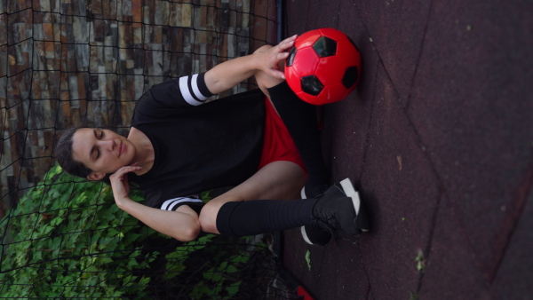 Beautiful female football player with a ball in her hand. The woman plays soccer for relaxation. Concept of mental health and sport.