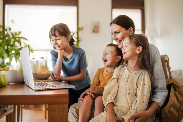 Mom and kids watching entertaining videos on mom's work laptop. Remote work and home office for single mother with children.