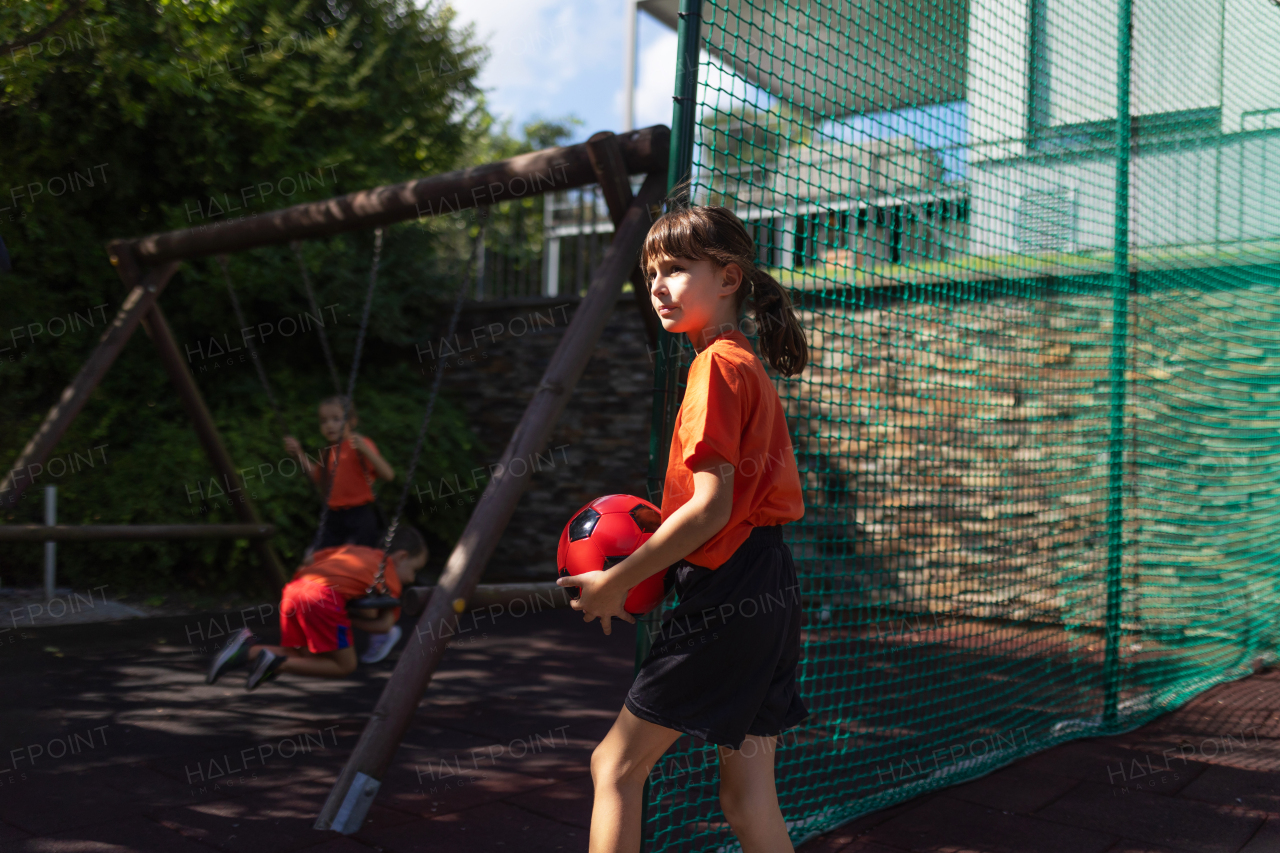 Siblings playing football, dressed in football jerseys. The family as one soccer team. Fun family sports activities outside in the backyard or on the street.